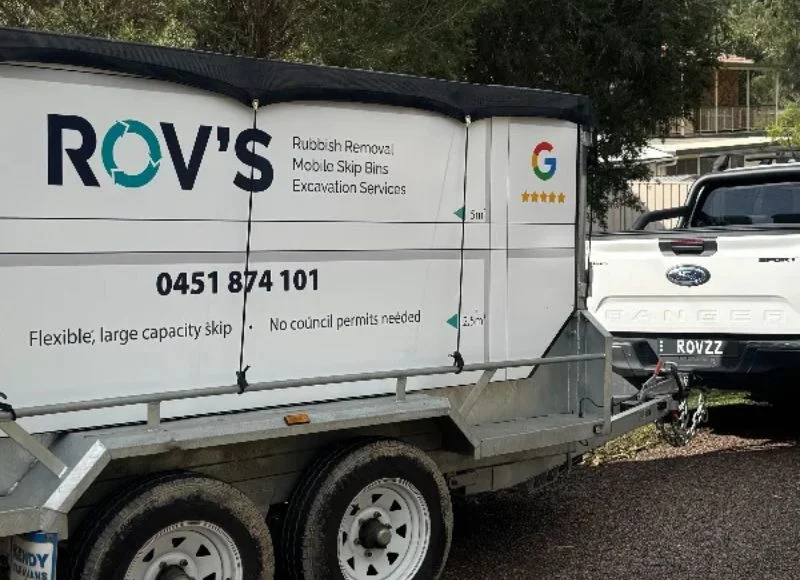 ROV’S mobile skip bin trailer attached to a pickup truck with rubbish removal signage and contact number.